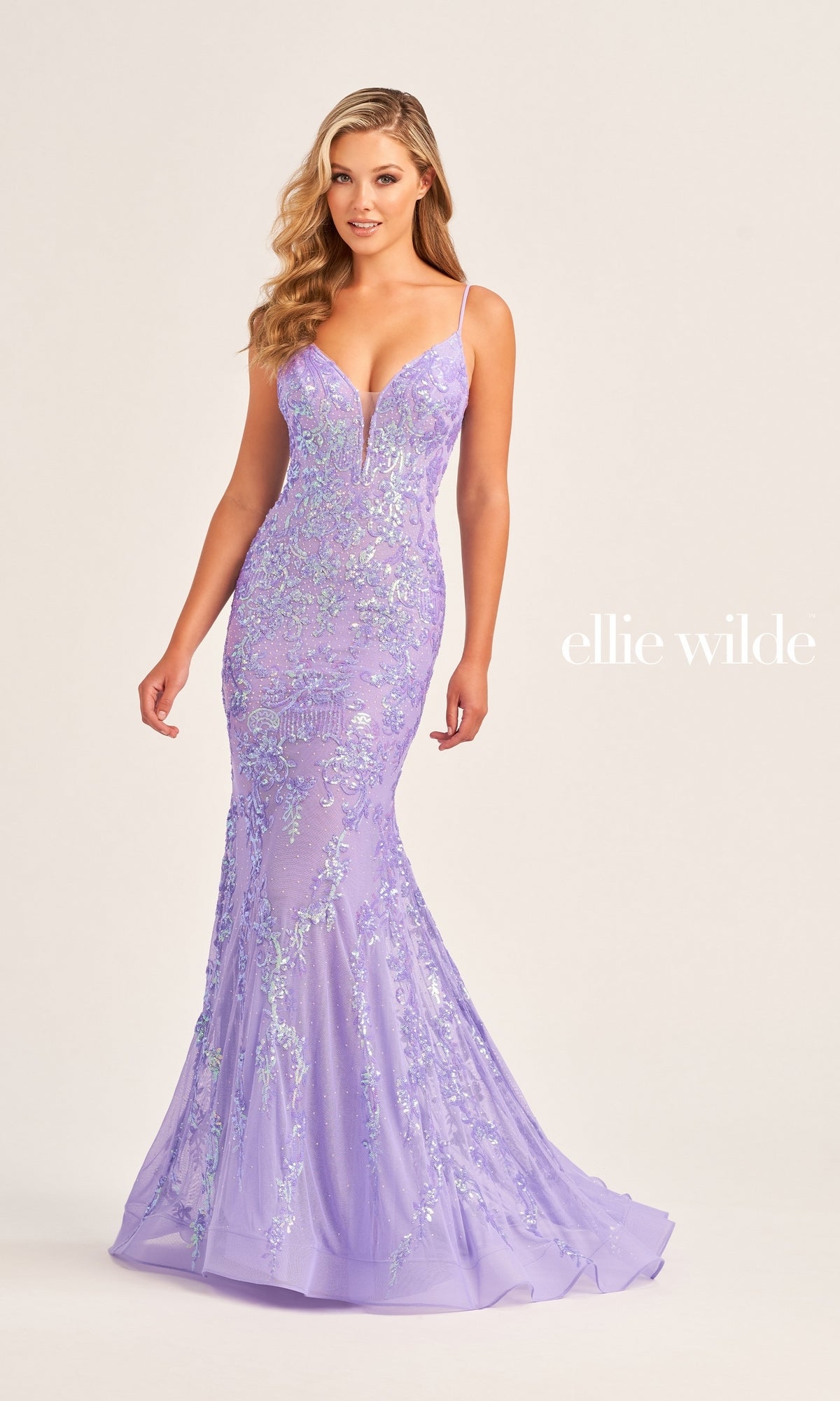 A woman wears the Ellie Wilde Long Mermaid Designer Dress EW35048, a fitted lavender sequin gown with thin straps and shimmering embellishments, standing against a plain background. Text reads